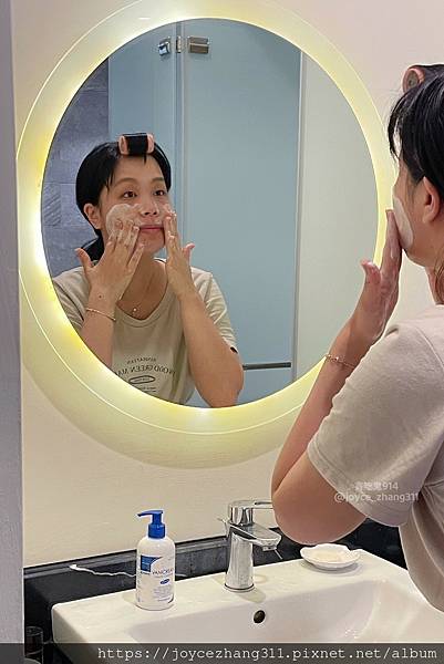 貪吃鬼914拍攝Joyce站在洗手台化妝鏡前，將薇霓肌本胺基酸調理潔膚露豐富又細緻的泡泡抹在臉頰肌膚上
