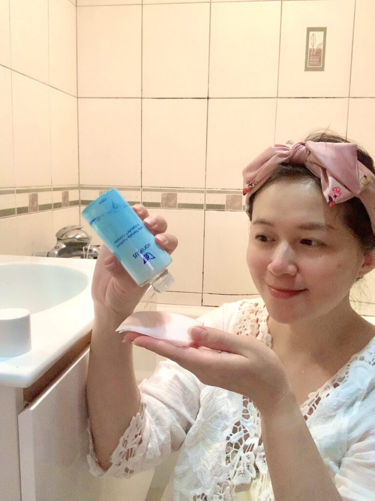 點點家的日常分享拍攝點點媽咪在浴室空間裡將薇霓進階極雪耳精露倒在手心中的化妝棉上