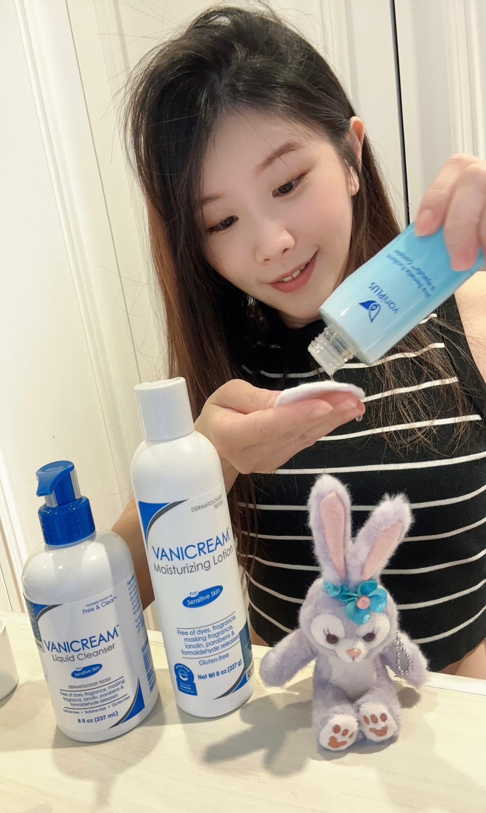 薇琪の萬得窩拍攝vicky將薇霓進階極潤雪耳精露到在手中的化妝棉上，周圍有薇霓肌本無油安膚清爽調理乳液與薇霓肌本胺基酸調理潔膚露還有一隻史黛拉兔娃娃