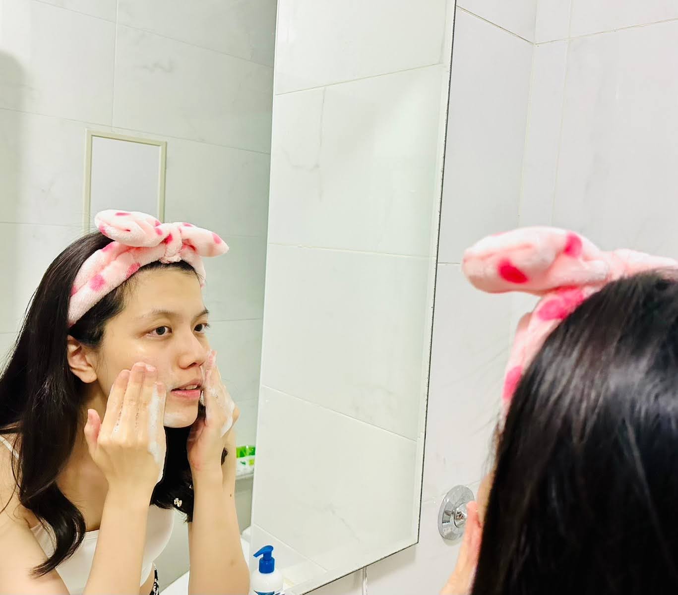 Dora & Rocky 食不湘瞞拍攝媽媽在浴室鏡子前清潔臉部肌膚，周圍有一瓶薇霓肌本胺基酸調理潔膚露