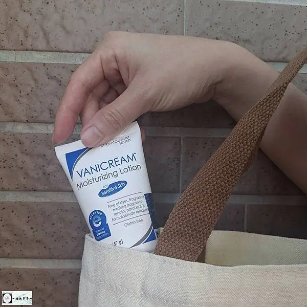 照片中，薇霓肌本無油安膚清爽調理乳液旅行瓶被放置一個淺色帆布棉質手提袋的開口處，一隻手輕輕握著乳液的軟管，將其展示在袋子中。