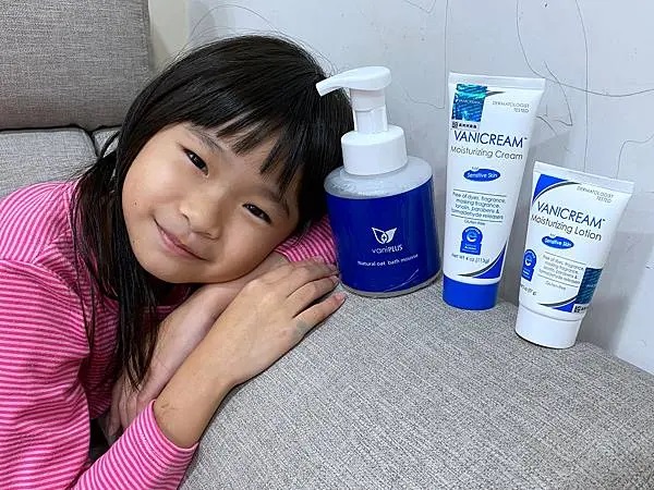 這張照片展示了一位可愛的小女孩和三款護膚產品vaniPLUS天然燕麥潔膚慕斯、VANICREAM薇霓肌本全日高效修護保濕乳霜和薇霓肌本無油安膚清爽調理乳液旅行瓶。