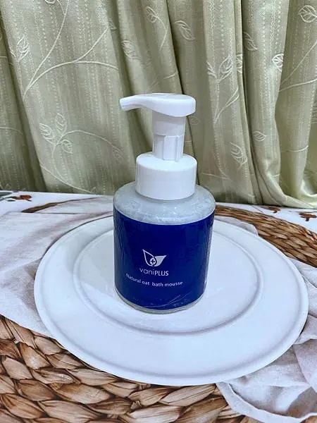 照片以居中的方式展示了vaniPLUS天然燕麥潔膚慕斯，白色的盤子和淺色的背景使產品本身更加突出。柔和的光線營造出一種乾淨和自然的感覺。