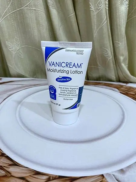 照片以居中的方式展示了VANICREAM薇霓肌本無油安膚清爽調理乳液旅行瓶，白色的盤子和淺色的背景使產品本身更加突出。整體的燈光柔和，營造出一種乾淨和專業的產品展示效果。