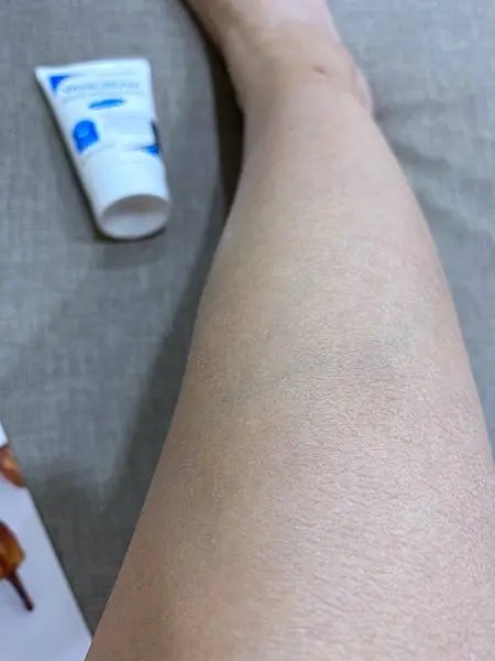 這張照片展示了一條腿和一條VANICREAM薇霓肌本無油安膚清爽調理乳液旅行瓶的軟管。