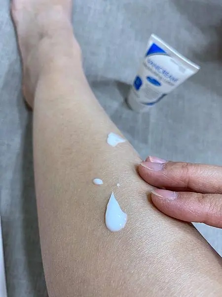 這是一張展示VANICREAM薇霓肌本無油安膚清爽調理乳液旅行瓶被擠在腿上並準備塗抹的照片，突顯了產品的使用情境。