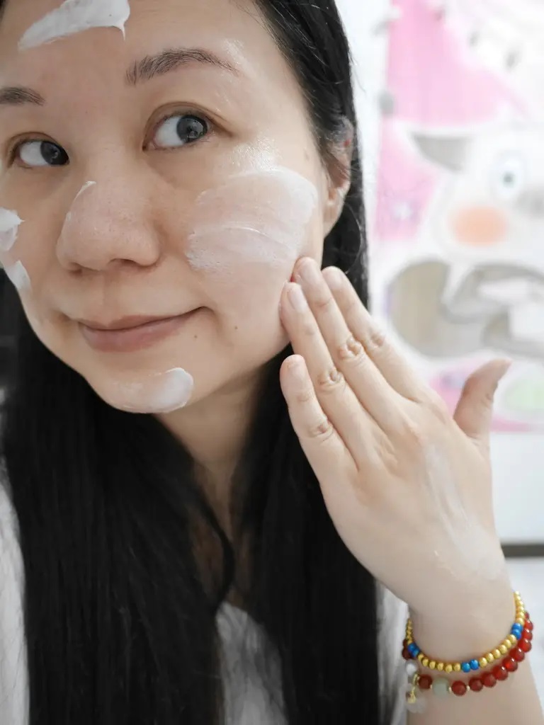 女性將薇霓肌本全日高效修護保濕乳霜塗抹於臉部額頭與雙頰，展現實際保養使用情境，膚觸自然透亮