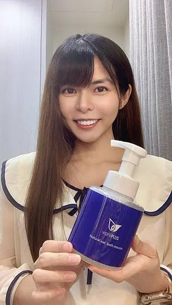 女性微笑展示薇霓進階天然燕麥潔膚慕斯，雙手手持產品瓶身，背景簡約室內空間，呈現親和感與潔膚推薦氛圍