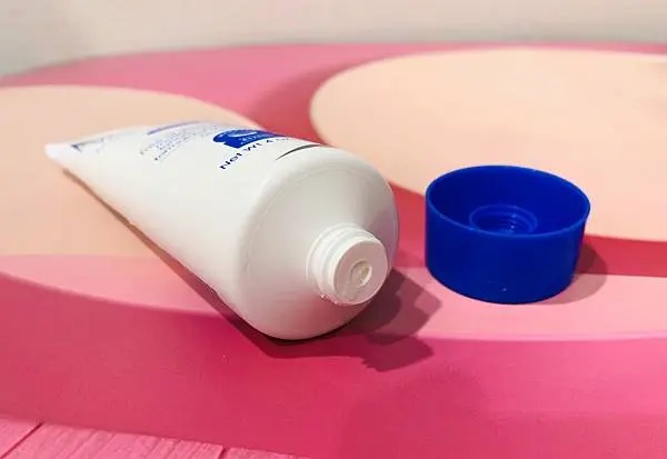 薇霓肌本全日高效修護保濕乳霜開封後瓶口展示，鋁膜已移除但尚未擠出乳霜，瓶蓋放置於一旁，呈現使用前準備狀態