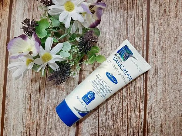 Vanicream薇霓肌本全日高效修護保濕乳霜，擺放於木質桌面並搭配白色與紫色花卉裝飾，展現溫和修護的保養氛圍