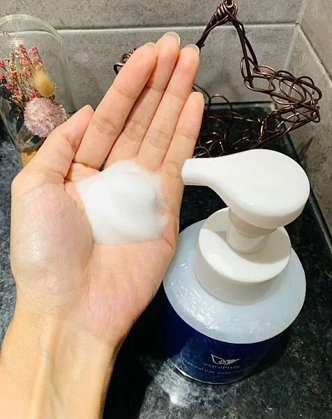 薇霓進階天然燕麥潔膚慕斯擠出後的泡沫展示於手心，泡體蓬鬆綿密，背景為浴室洗手台與乾燥花擺設，呈現清新保養氛圍